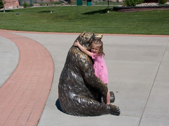 Nena abrazando a una estatua de oso